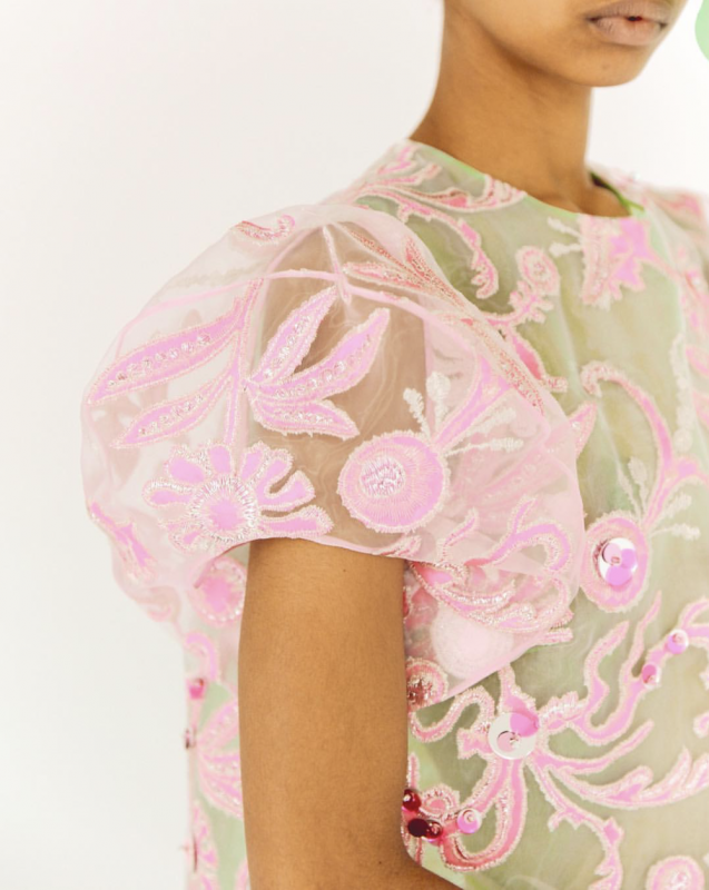 Sleeve detail of vibrant pink sequin pattern on sheer white dress.